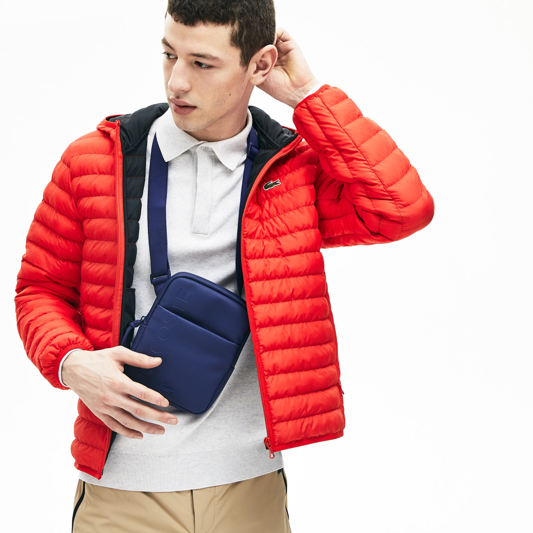 حقيبة صغيرة مسطحة بسحاب للرجال مزدانة بشعار العلامة التجارية من مجموعة L.12.12 حقيبة صغيرة مسطحة بسحاب للرجال مزدانة بشعار العلامة التجارية من مجموعة L.12.12